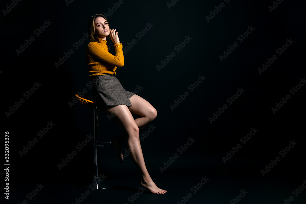 young girl sitting on a high chair against a dark background, copy space, low key photo