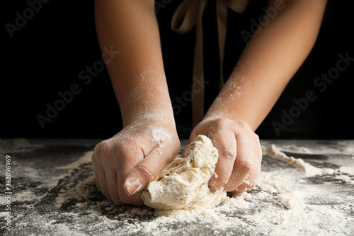 Woman kneading dough for pizza at grey table, closeup