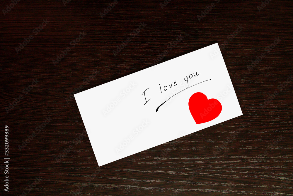 Rectangular white envelope on a wooden table. The inscription on the envelope I love you and my heart.