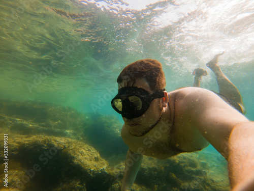 man swimming underwater with snorkeling musk