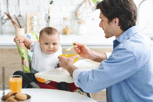 Dad feeding his baby with healthy untasty food photo