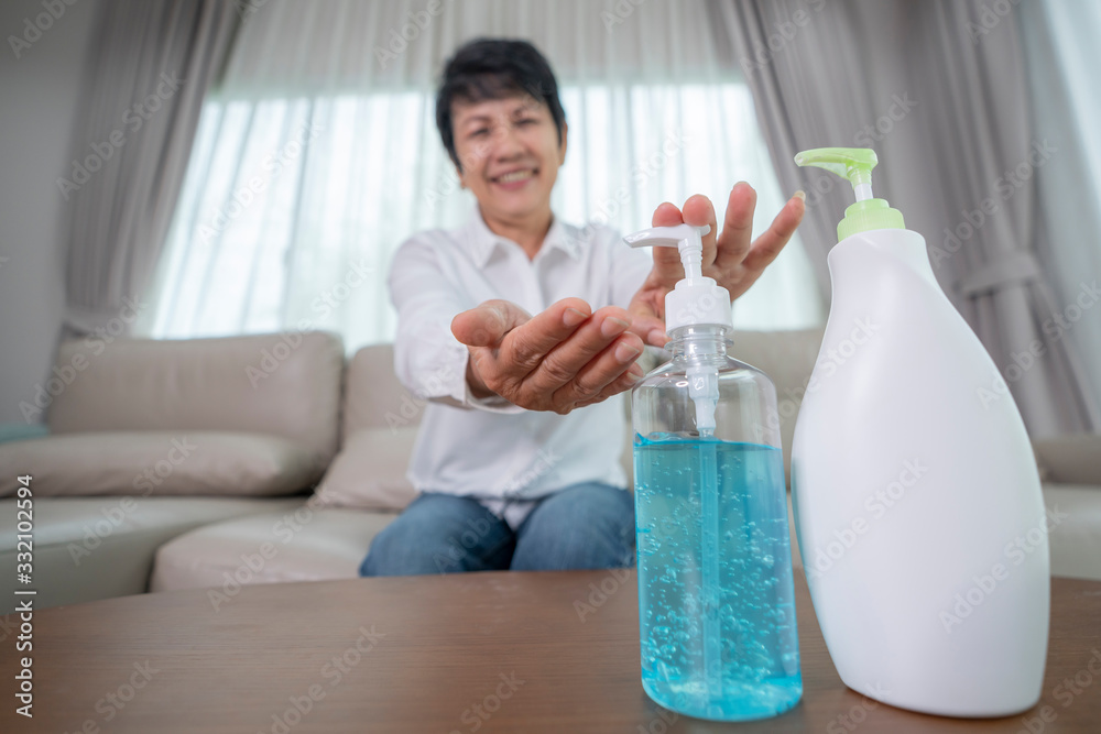 selective focus to hand and alcohol, Old people in asia usd alcohol gel and moisturizer cleaning her hands for prevent a covid19 virus in living room.