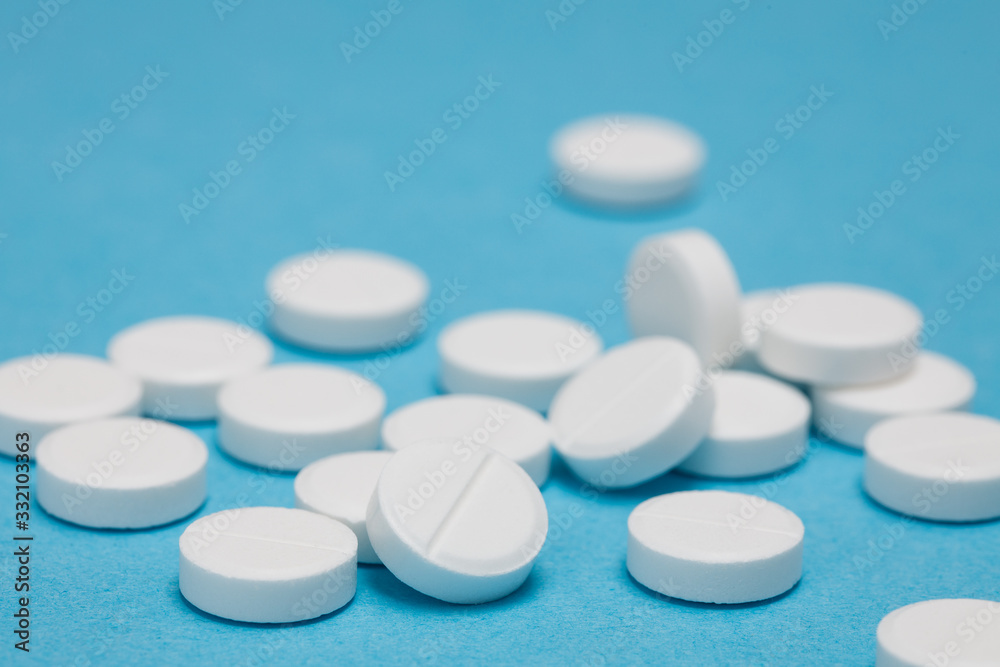White round pills on a blue background White round pills on a blue background