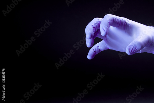 A purple claw in medical glove scares virus on a black background