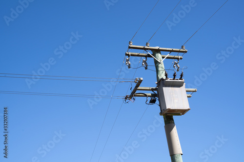 Electric pole under blue sky in rural, New Zealand.