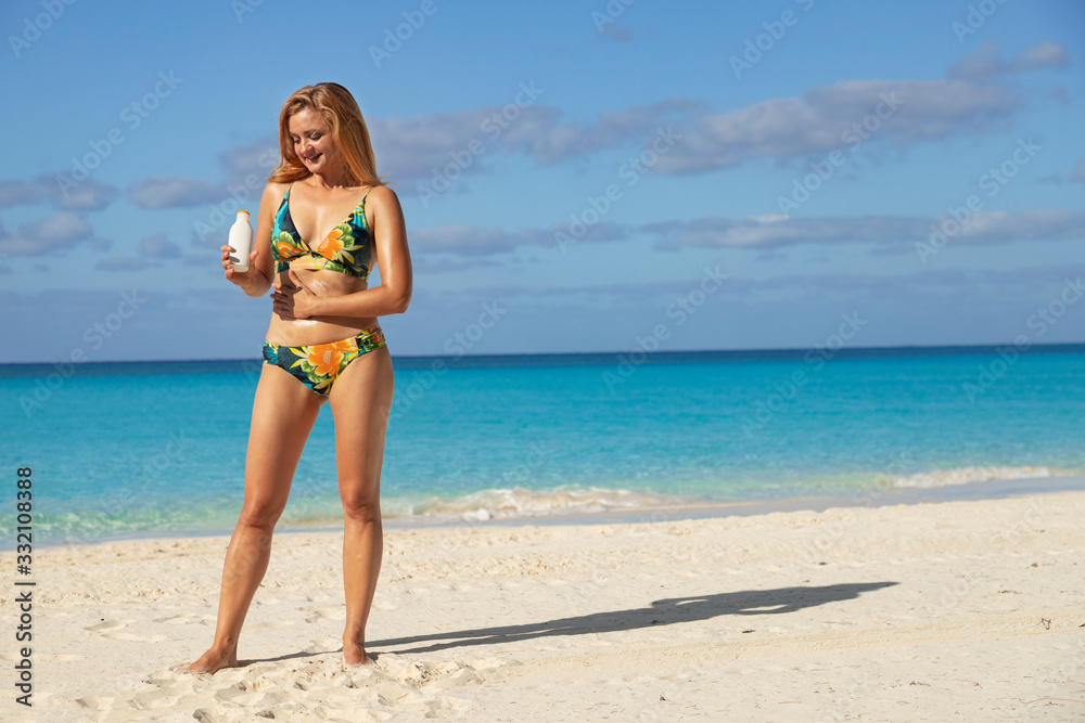 Girl on the beach with sunscreen. Beautiful blonde on the beach. Sun protection