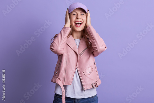 Picture of beautiful charming sweet female opening mouth widely, laughing, being in high spirits, covering her ears with both hands, no hearing, wearing casual clothes. People and emotions concept. photo