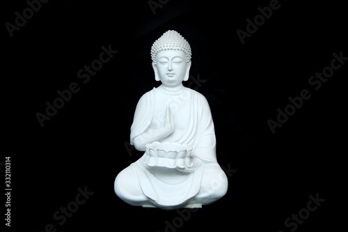Leinwand Poster The white statue of the calm sitting buddha isolated in a black background