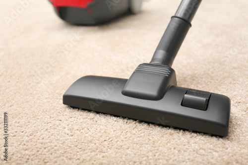 Removing dirt from carpet with vacuum cleaner indoors, closeup