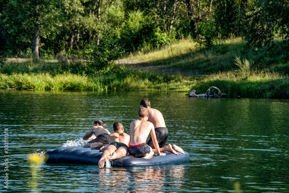 Boys swimming having fun on a rubber raft on a river in summer. Boys swimming having fun on a rubber raft on a river in summer.