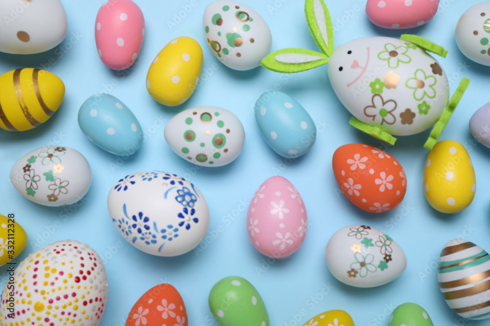 Colorful Easter eggs on light blue background, flat lay