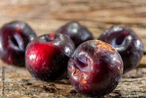 Fresh fruits of red plum (Prunus domestica) on aged wooden background
