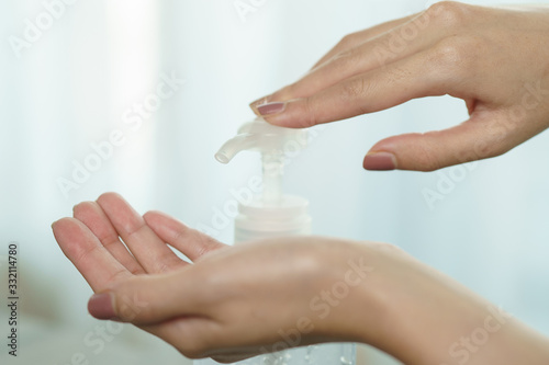Female hands using wash hand sanitizer gel pump dispenser. Clear sanitizer in pump bottle  for killing germs  bacteria and virus.