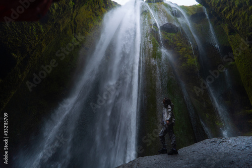 Traveler stunned by Gljufrabui waterfall cascade in Iceland. Located at scenic Seljalandsfoss waterfall South of Iceland, Europe. It is top beautiful destination of popular tourist travel attraction.