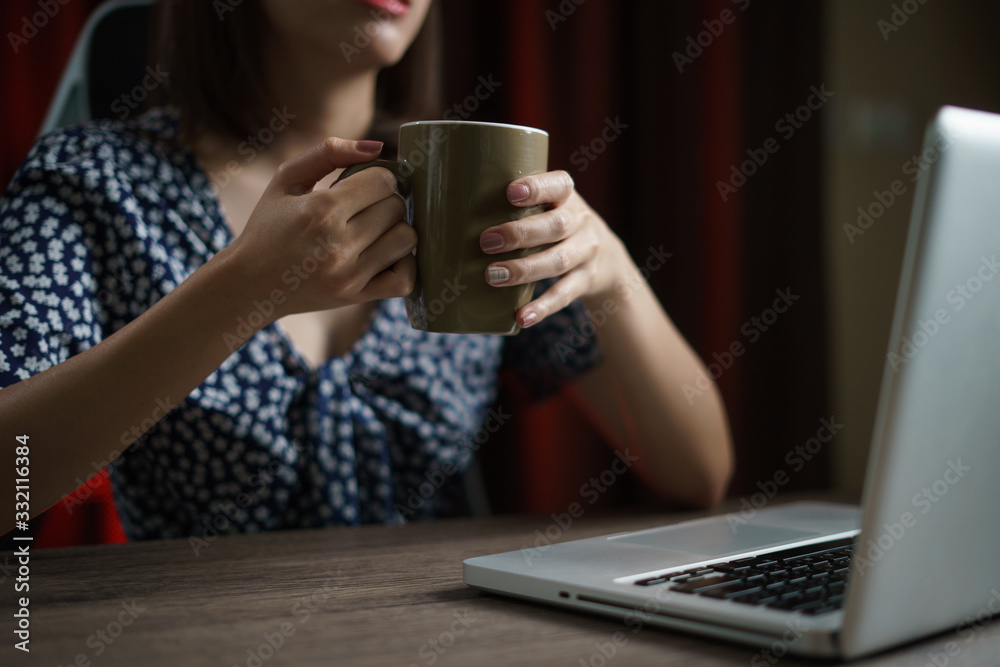 Woman working from home using computer and drinking cup of tea, closeup portrait indoor. Woman working from home using computer and drinking cup of tea, closeup portrait indoor.