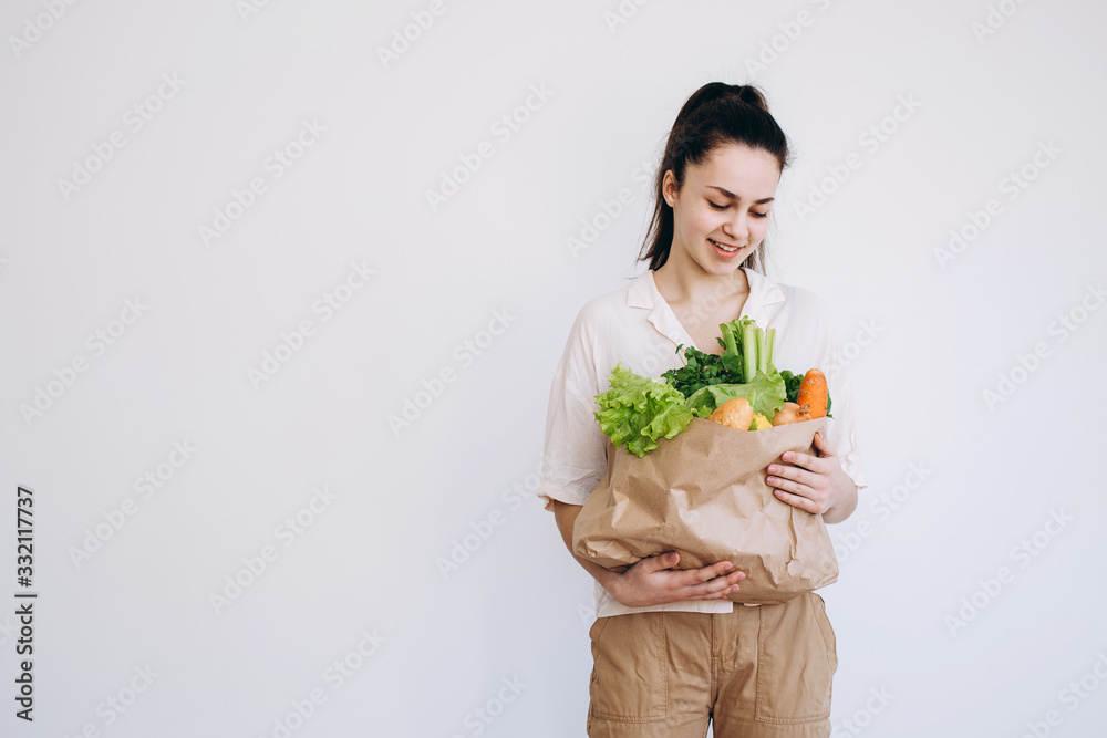 Hand with an eco paper bag with vegetables.Young hipster lifestyle girl holding paper bag with vegetables. Zero waste food shopping. eco natural concept Hand with an eco paper bag with vegetables.Young hipster lifestyle girl holding paper bag with vegetables. Zero waste food shopping. eco natural concept