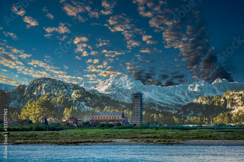 Old church in field by Mountains with bell tower covered in scaffolding