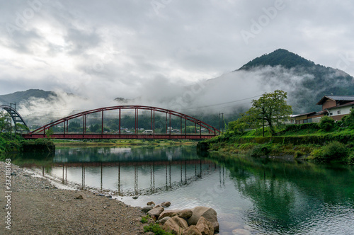 Red bridge and river in the mountain valley. Japanese countryside landscape