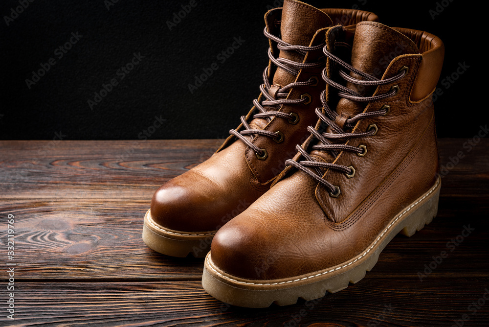 Red winter leather boots on dark wooden background.