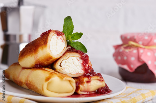 Thin crepe pancake rolls stuffed with cottage cheese, served with raspberry jam. Traditional Russian cuisine. Crepe week. Maslenitsa. photo