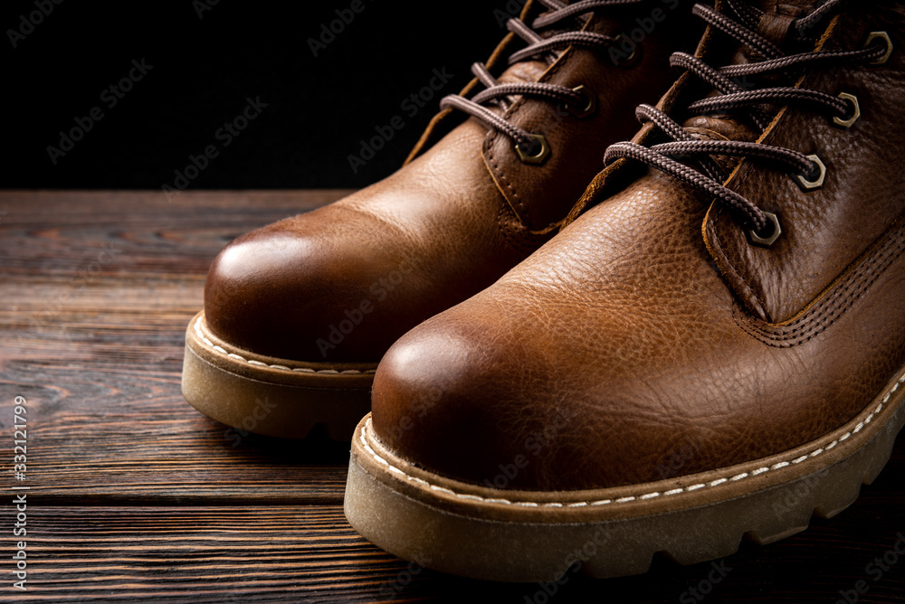 Red winter leather boots on dark wooden background.