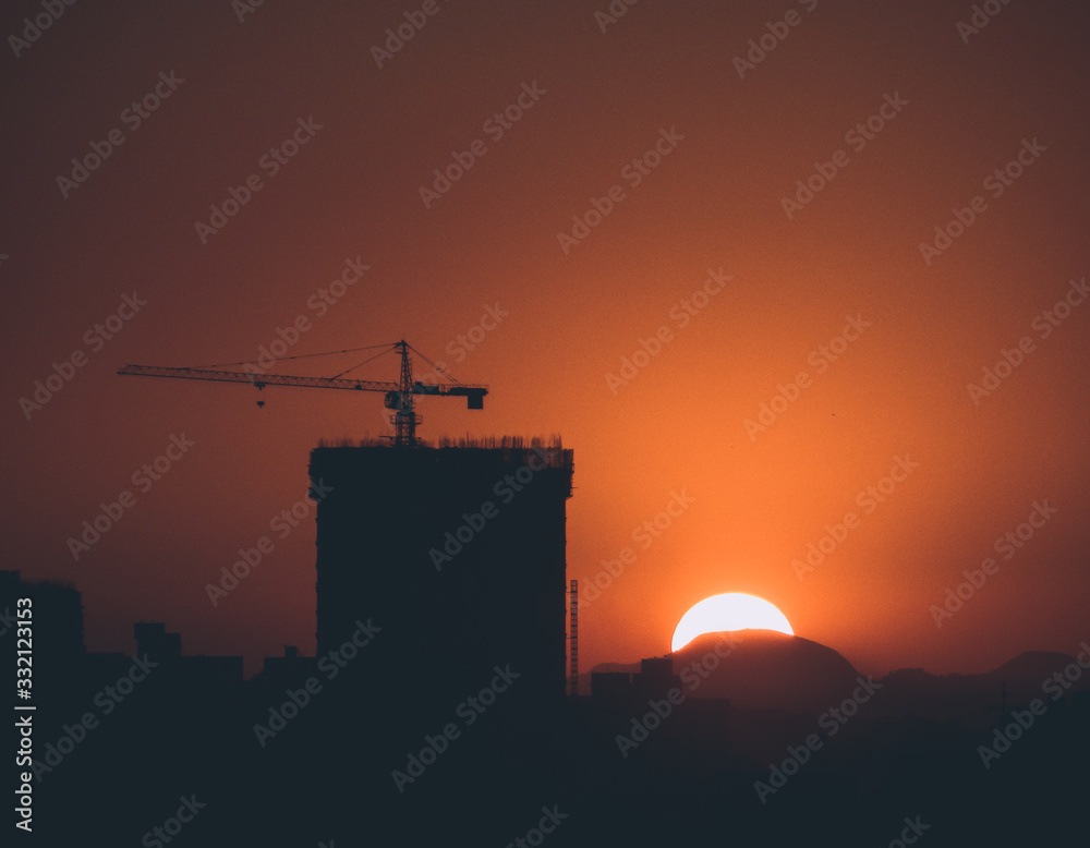 Silhouette of a building under construction at sunset
