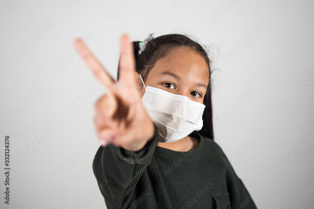 Lttle girl with medical mask show v sign with hand, healthcare and infection control. Concept of positivism against the infection of the coronavirus, quarantine kids. Lttle girl with medical mask show v sign with hand, healthcare and infection control. Concept of positivism against the infection of the coronavirus, quarantine kids.