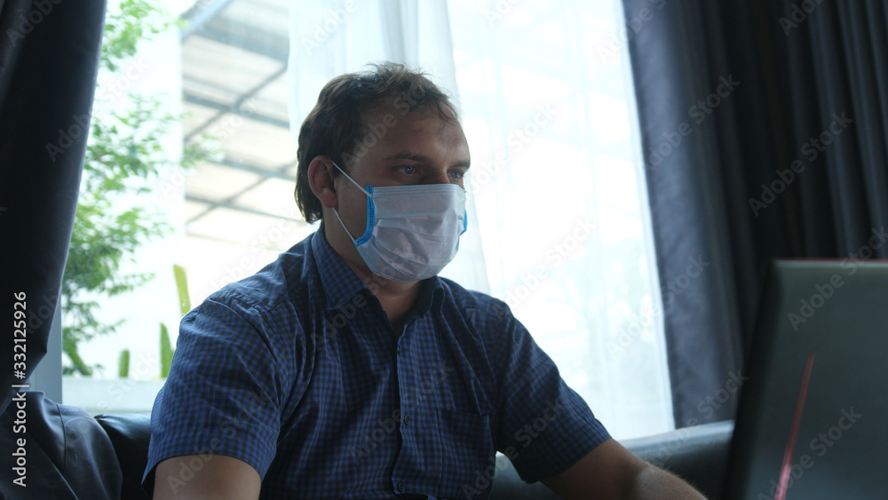 Man works from home in quarantine wearing a face mask