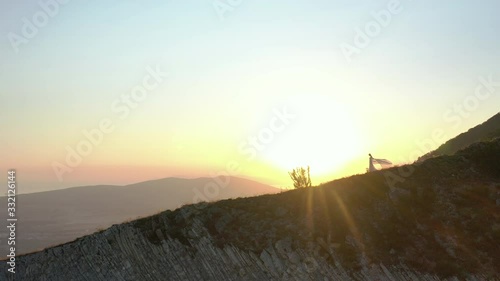 Aerial shots of a girl at sunset in a flowing dress, walking along a mountain slope in contour light