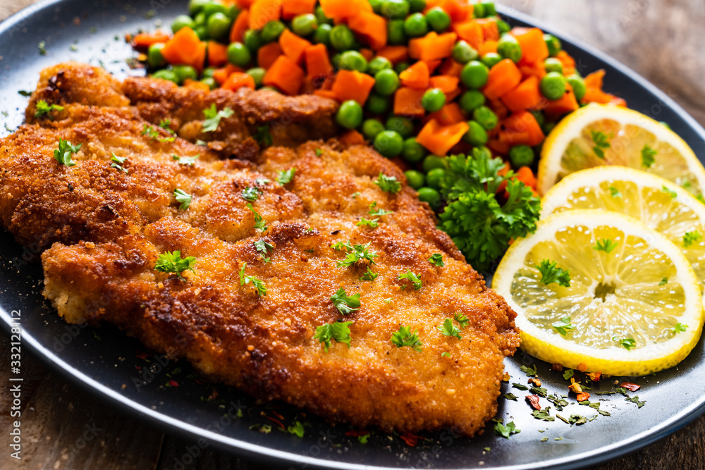 Schnitzel with boiled carrot and peas on wooden background Schnitzel with boiled carrot and peas on wooden background