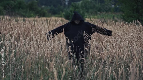 Black death in the field in autumn. Scary view of a witch evil turning around itself outdoors. Dark wizard among nature. photo