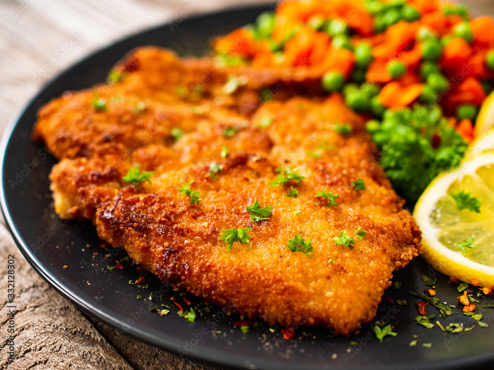 Schnitzel with boiled carrot and peas on wooden background Schnitzel with boiled carrot and peas on wooden background