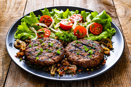 Barbecue steaks with vegetables on wooden background