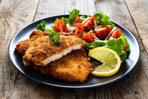 Cuadro en lienzo Pork chops with lemon and vegetable salad on wooden background