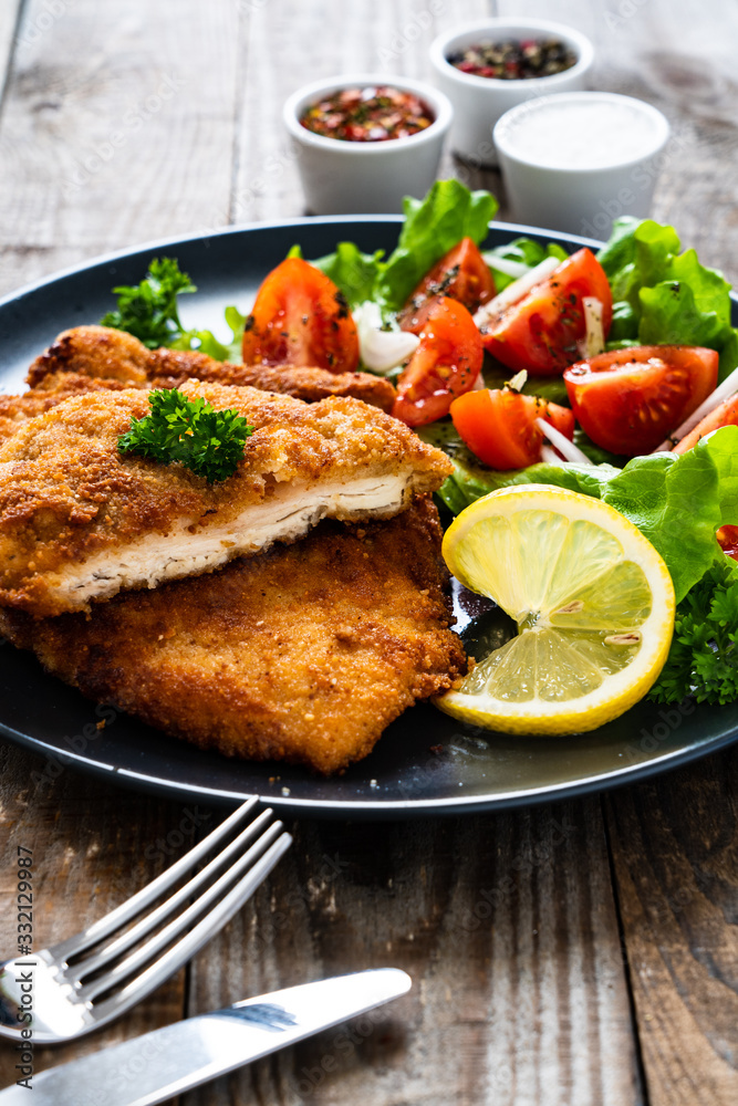 Pork chops with lemon and vegetable salad on wooden background Pork chops with lemon and vegetable salad on wooden background