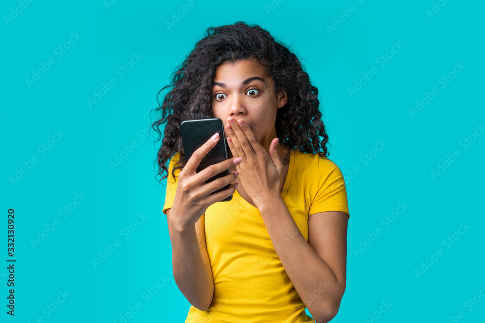 Portrait of beautiful smiling dark skinned girl wearing bright colored yellow t-shirt isolated over blue background Portrait of beautiful smiling dark skinned girl wearing bright colored yellow t-shirt isolated over blue background
