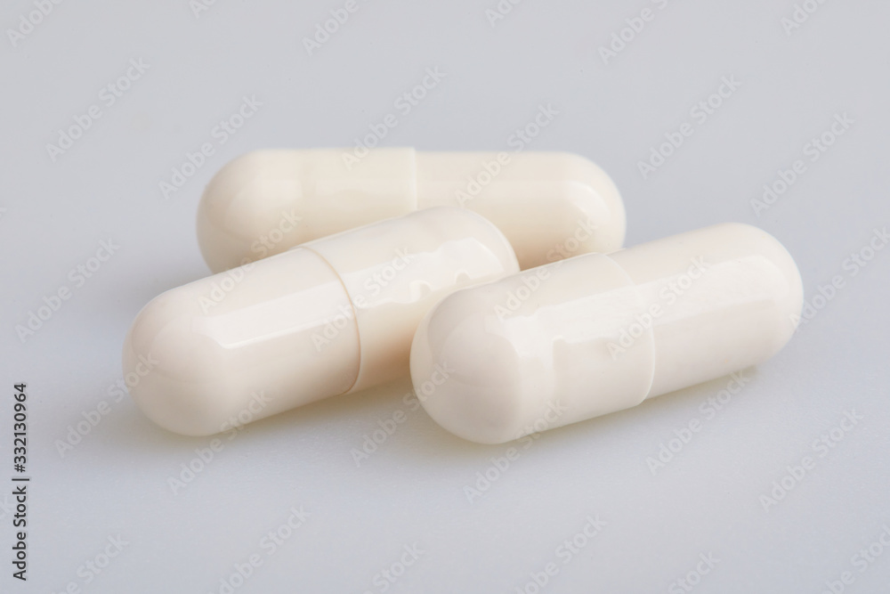White gelatin capsules with powder, on white background. Pharmaceutical concept. White gelatin capsules with powder, on white background. Pharmaceutical concept.