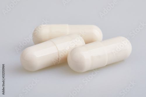 White gelatin capsules with powder, on white background. Pharmaceutical concept.