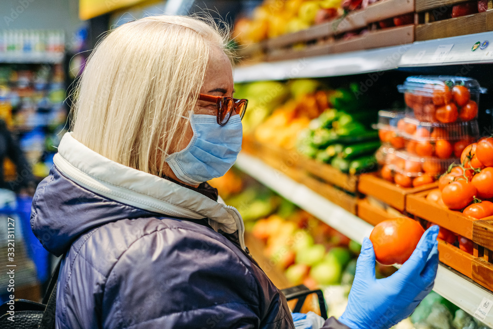 Old woman in medical masks is shopping in the supermarket looking for the food