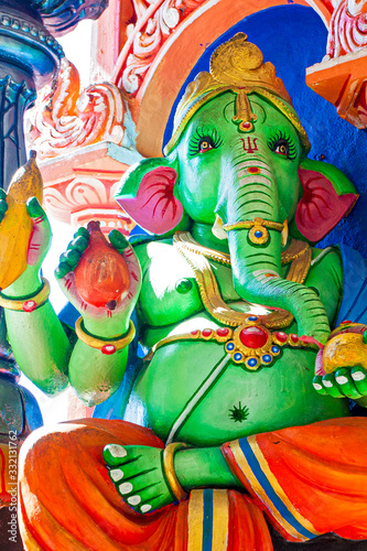 Representation of Hindu gods and tourists climbing a colorful stairs leading to the Batu Caves in the background. Kuala Lumpur, Malaysia photo