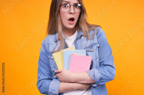 Surprised student with open mouth with books in hands in glasses.