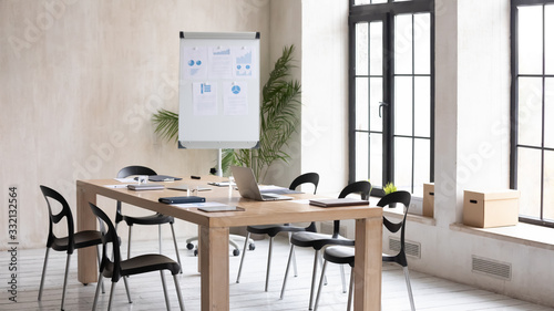 Fototapeta Naklejka Na Ścianę i Meble -  Empty modern loft office space with wooden table, electronic appliances notebooks ready for meeting, working workplace with no people prepared for briefing, whiteboard presentation or training