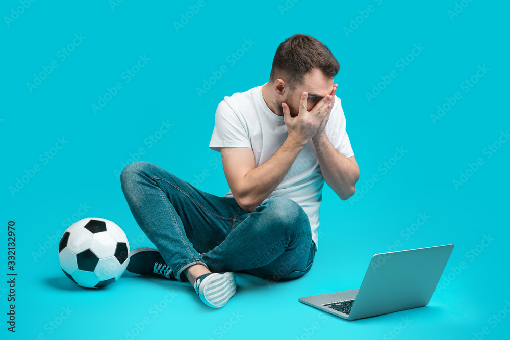Young bearded man betting online at bookmaker's website Young bearded man betting online at bookmaker's website