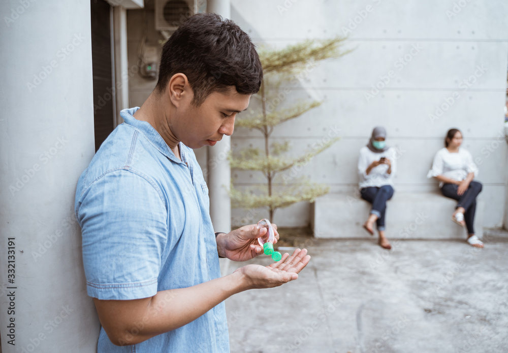man appying hand sanitizer while keeping distance from his friend man appying hand sanitizer while keeping distance from his friend