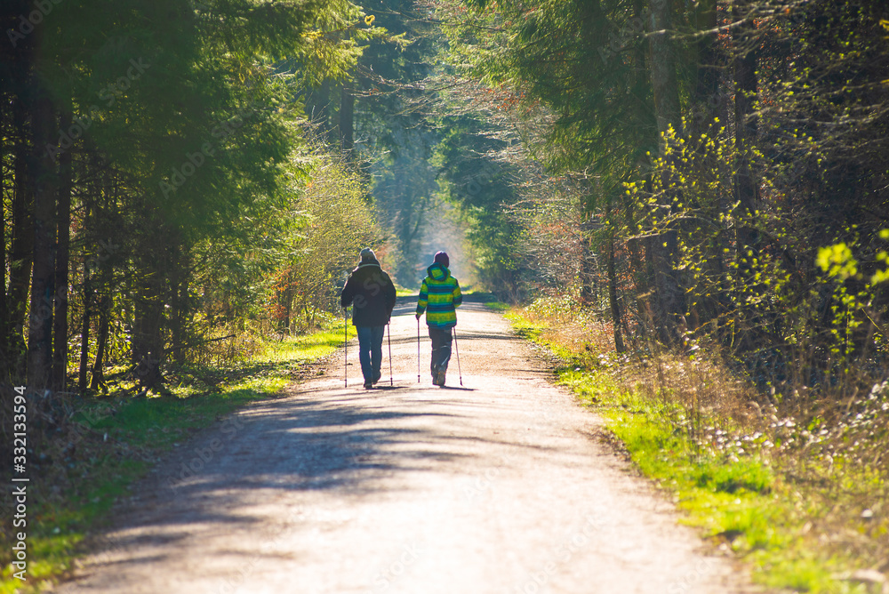 A mother and her son  do nordic walking on a forest path during the corona virus lockdown in germany, with families and single persons allowed to go out on strolls.