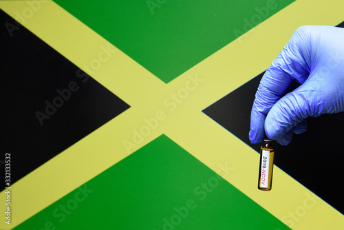 Corona virus or Covid-19 in Jamaica , sample blood tube in hand with Jamaica flag on background
