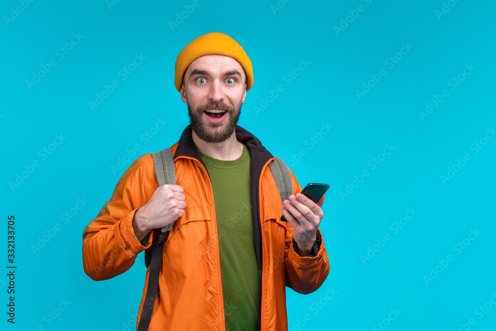 Half length studio portrait of casually dressed smiling male tourist with a backpack isolated over blue background Half length studio portrait of casually dressed smiling male tourist with a backpack isolated over blue background