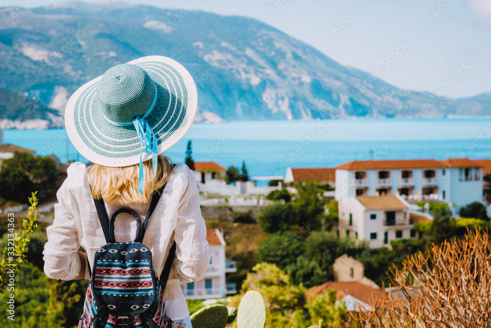 Tourist female with blue sun hat enjoying greek cute and vivid colored Assos town on Kefalonia island, Greece