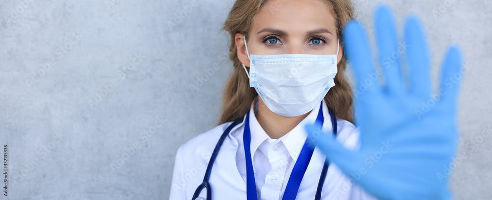 Medical staff preventive gear against coronavirus. Female doctor in face mask showing stop sign with her hand. - obrazy, fototapety, plakaty 