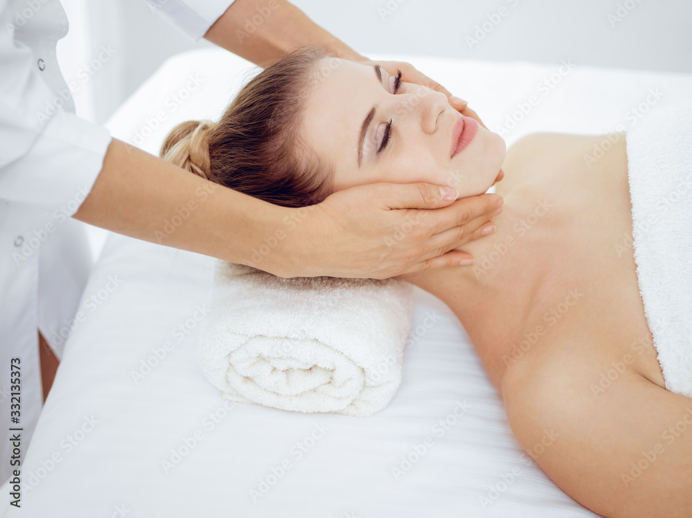 Young and blonde woman enjoying facial massage in spa salon. Beauty concept Young and blonde woman enjoying facial massage in spa salon. Beauty concept